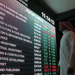 متعامل يتابع شاشة إلكترونية تعرض أسعار أسهم في البورصة