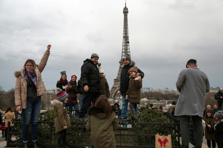 سياح يلتقطون صورا امام برج ايفل في باريس 