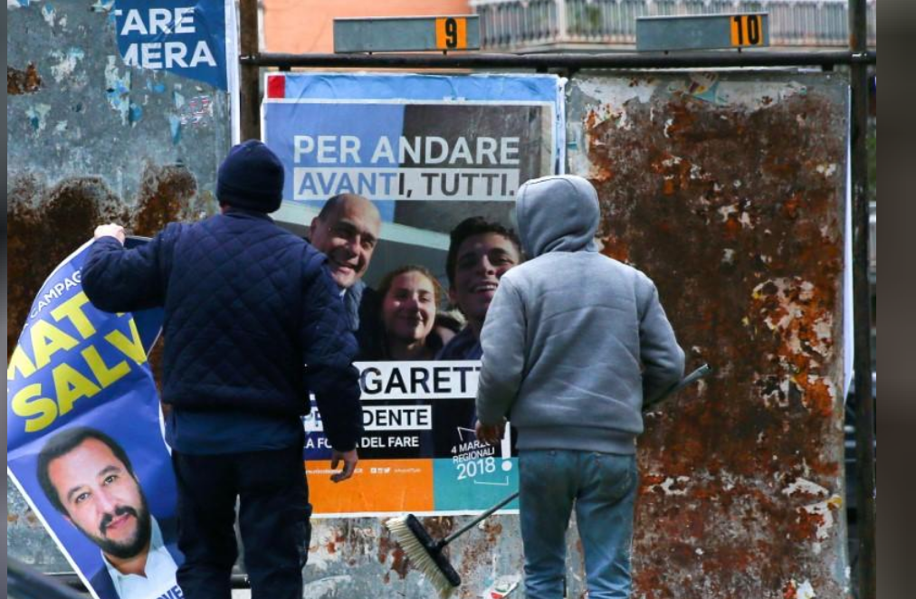 رجلان يعلقان ملصقات انتخابية في روما 