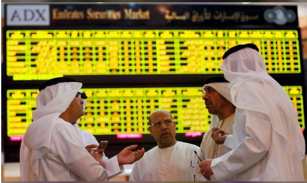 مستثمرون أمام لوحات إلكترونية تعرض مؤشرات الأسهم في بورصة أبوظبي 