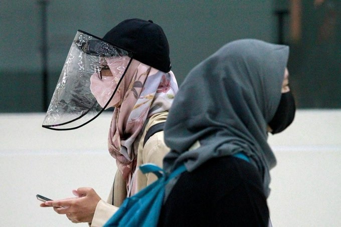 Women are pictured wearing a protective face mask and face shield in Jakarta