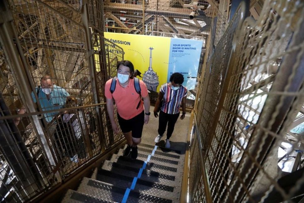People wearing protective face masks climb the stairs as they visit the Eiffel Tower in Paris on its reopening day to the public following the coronavirus disease (COVID-19) outbreak 
