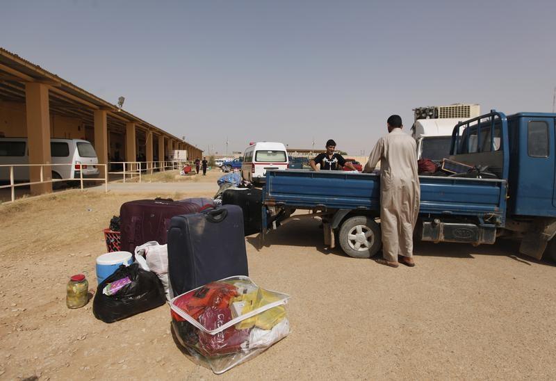 صورة من أرشيفية لسوريين يفرغان الشاحنة من أمتعتهما في مخيم لاجئين مؤقت داخل العراق بعد عبور الحدود العراقية السورية عند موقع البوكمال-القائم الحدودي.