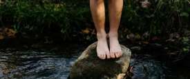 A child balances on a rock in a river 