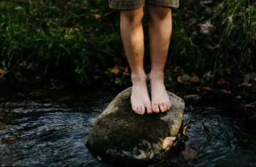 A child balances on a rock in a river 